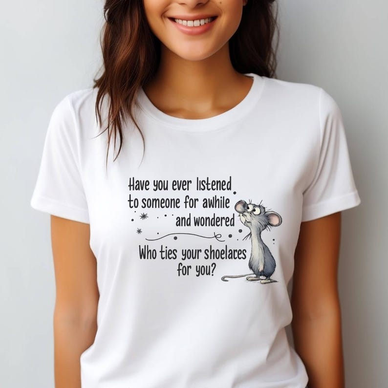 May include: White t-shirt featuring a cartoon mouse looking upwards with the text "Have you ever listened to someone for awhile and wondered Who ties your shoelaces for you?" The shirt has short sleeves.