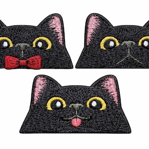 May include: Three embroidered patches shaped like black cat heads with pink inner ears and large yellow eyes. One cat wears a red bow tie, one has a neutral expression, and one has a pink tongue sticking out. The patches have a flat base.