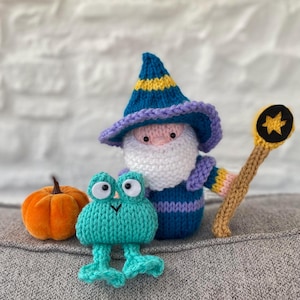 May include: A selection of handmade knitted toys, featuring a wizard with a blue hat and staff, a teal frog, and an orange pumpkin. The wizard has a white beard and a purple and yellow hat. The frog has large, round eyes.