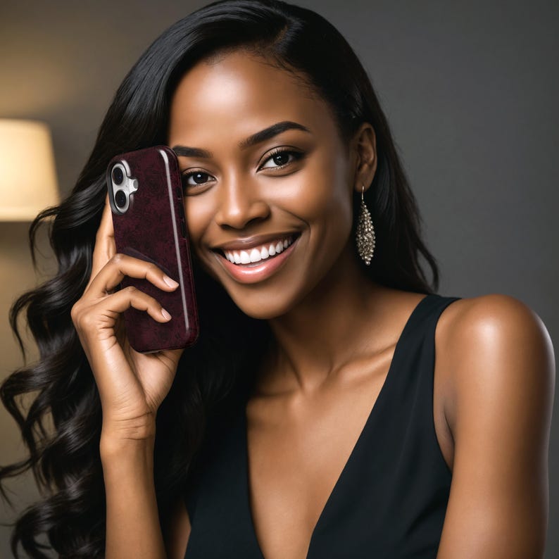 May include: A burgundy phone case with a textured pattern. The phone case is held up to the ear. The image features a woman with long, dark hair and a black dress. She is smiling and wearing dangling earrings.