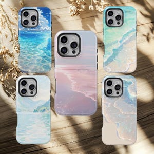 May include: Five phone cases with ocean-themed designs. The cases feature images of the sea, waves, and beaches in shades of blue, turquoise, and pink. The cases are arranged on a wooden surface with dried plants.