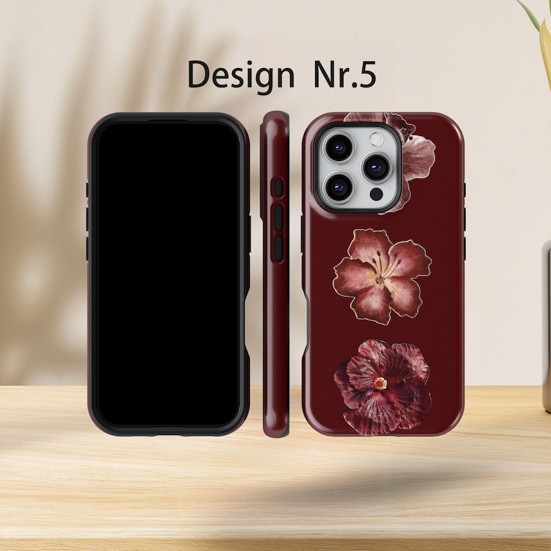 May include: Three burgundy phone cases are displayed, showing different angles. The cases have a floral pattern with red and pink flowers. The text "Design Nr.5" is visible at the top of the image.