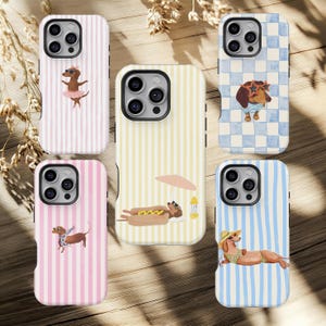 Op de afbeelding: Collectie telefoonhoesjes met teckel illustraties. Ontwerpen omvatten een hond in een tutu, een hond met een zonnebril en een hond die ontspant op het strand. De hoesjes hebben gestreepte en geblokte patronen in roze, geel en blauw.