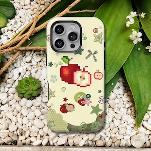 Op de afbeelding: Een lichtgele telefoonhoesje met een pixelafbeelding van een rode appel en een appelschijfje. Het ontwerp bevat verspreide groene sterren, kleine strikjes, knopen en wervelpatronen. Het hoesje heeft een zwarte uitsparing voor de cameralens.