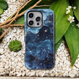 Puede incluir: Una funda para smartphone con un diseño de nebulosa azul oscuro y blanco. La funda presenta un patrón de cielo estrellado con nubes arremolinadas y estrellas brillantes. La funda tiene un parachoques protector alrededor de la cámara.