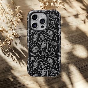 May include: Black phone case featuring a repeating pattern of white animal skulls, bones, and skeletal elements. The case has a glossy finish and a black border. The design is detailed and intricate, creating a gothic or macabre aesthetic.