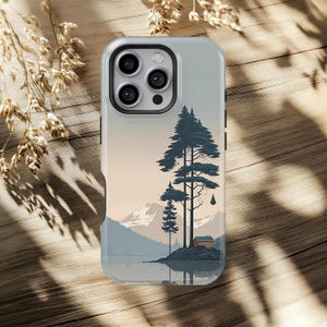 May include: A light gray phone case featuring a landscape scene with pine trees, mountains, and a small cabin. The design has a serene, natural aesthetic, with a color palette of blues, greens, and beige.