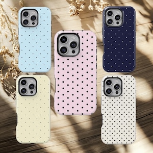 May include: Five smartphone cases in a variety of colours: pale blue, pink, navy, cream, and white. Each case has a pattern of small black polka dots. The cases are designed to fit a smartphone and have a protective bumper.