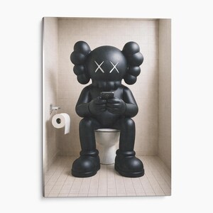 May include: A matte black KAWS-style character figure with X-shaped eyes and rounded ears, sitting on a white toilet while holding a small black smartphone. A roll of white toilet paper hangs on a silver holder attached to the tiled wall nearby.