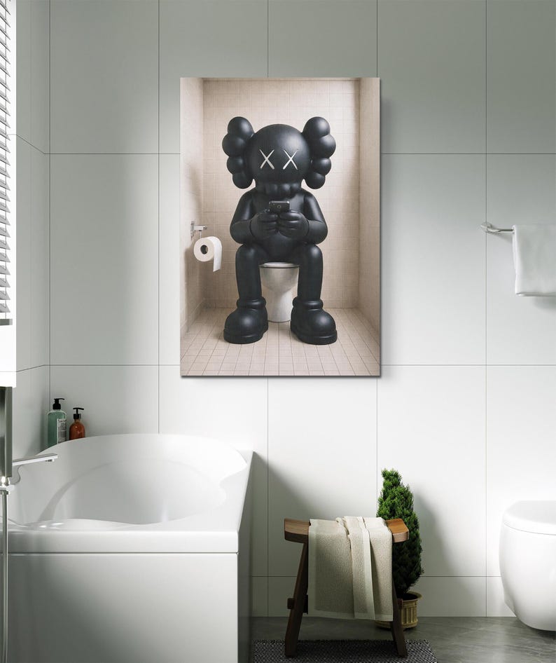May include: A black KAWS character figurine with X-shaped eyes sitting on a white toilet while holding a small rectangular device. The figure has large rounded ears and oversized feet, positioned in a tiled alcove with a toilet paper roll holder.