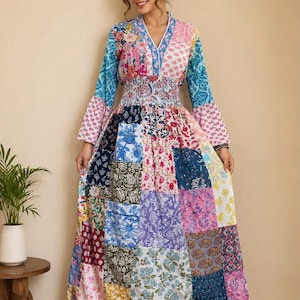 Puede incluir: Un vestido largo de manga larga con un diseño de patchwork que presenta varios estampados florales y botánicos en tonos azul, rosa, morado, amarillo y blanco. El vestido tiene cuello en V, cintura elástica fruncida y mangas acampanadas.