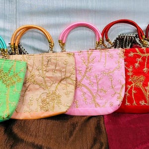 Puede incluir: Cinco bolsos bordados en fila, cada uno de un color diferente: verde, melocotón, rosa, rojo y burdeos. Los bolsos tienen asas a juego y detalles dorados, con intrincados bordados florales. Ideales para eventos.
