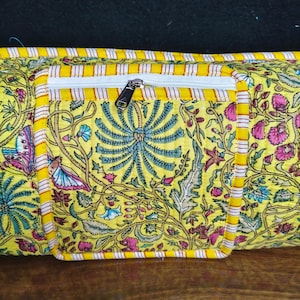 Puede incluir: Bolso amarillo con estampado floral y bolsillo con cremallera blanco. El bolso presenta un dise&ntilde;o floral colorido con detalles en rosa, azul y verde. Los bordes est&aacute;n ribeteados con tela a rayas amarillas y blancas.