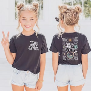 May include: Two girls wearing black t-shirts and denim shorts. The front of the shirts reads "Your Way's Better" in white script. The back of the shirts have a graphic with the same text, plus religious symbols and text.