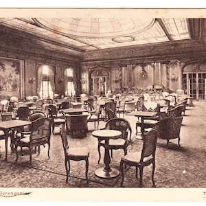 May include: Vintage sepia-toned postcard depicting the lounge of the Cunard R.M.S. Berengaria. The image shows a large room with tables, chairs, and ornate decor. The text "THE LOUNGE" is visible in the lower right corner.
