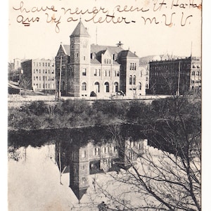 Peut inclure: Carte postale vintage en noir et blanc représentant le bureau de poste de Binghamton, N.Y. L'image montre le bâtiment avec un clocher se reflétant dans l'eau. Du texte manuscrit est visible en haut de la carte.