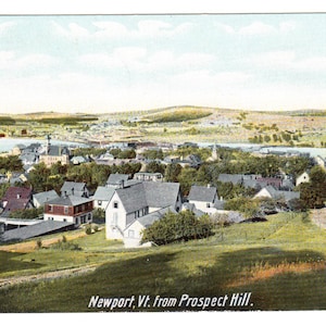 May include: A vintage postcard showing Newport, Vermont, from Prospect Hill. The image presents a scenic view of the town, featuring buildings, trees, and a body of water in the background. The sky is a light blue with some clouds.