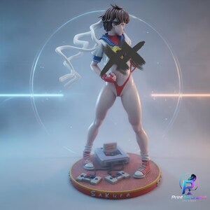May include: A figurine of a character with brown hair wearing a white sailor-style top, red gloves, and red trainers. The figure stands on a circular base featuring a game console with two controllers and the text "Sakura" printed on the front edge.