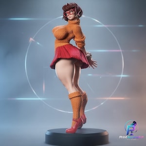 Pode incluir: Uma estatueta estilizada de uma personagem com cabelo castanho curto, óculos vermelhos, camisola de gola alta laranja, saia vermelha plissada, meias laranja até ao joelho e sapatos vermelhos. A figura está sobre uma base circular preta lisa.