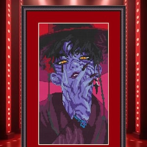 May include: Framed cross-stitch art featuring a stylized portrait of a person with purple skin, black hair, and long black fingernails. The artwork is set against a red background and framed in a black frame. The image is illuminated by spotlights.