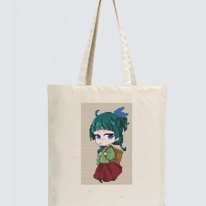 Op de afbeelding: Een crèmekleurige draagtas met een gepixeld beeld van een anime-achtig personage. Het personage heeft groen haar, een rode rok en een rugzak. De tas heeft lange handvatten om over de schouder te dragen.