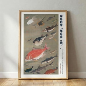 May include: A framed print featuring a Japanese artwork of various fish, including a large red snapper, pufferfish, and stingrays. The artwork is set against a muted green background with Japanese text and English translation. The frame is made of light-colored wood.