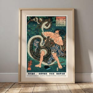Könnte beinhalten: Gerahmter Druck eines japanischen Holzschnittkunstwerks, das einen Mann zeigt, der mit einer riesigen Python kämpft. Das Kunstwerk verwendet lebendige Farben, wobei sich der Körper der Schlange um den Mann windet. Der Druck ist in einem Holzrahmen.