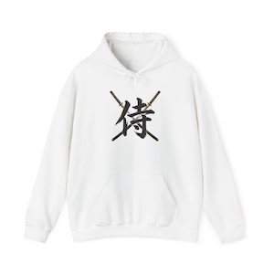 May include: White hooded sweatshirt with a front pocket and a drawstring. The design features a black and gold Japanese kanji symbol with two crossed swords. The sweatshirt is made of a soft material.