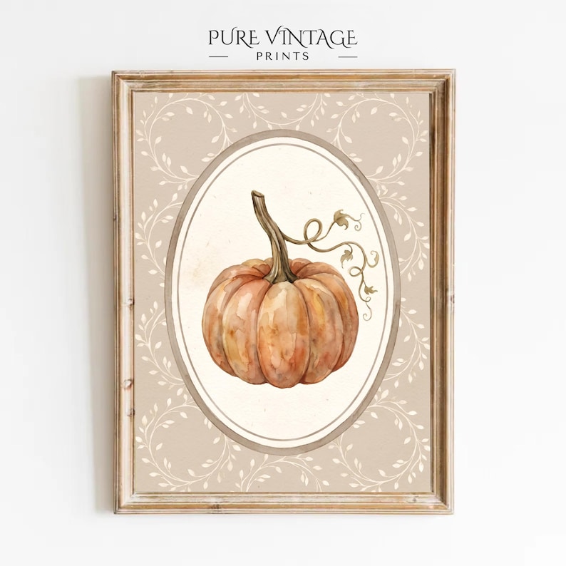 Puede incluir: Una l&aacute;mina de arte enmarcada con una ilustraci&oacute;n en acuarela de una calabaza naranja con tallo marr&oacute;n y zarcillos, centrada en un marco ovalado. El fondo es de color beige claro con un patr&oacute;n de hojas blancas que cubre toda la superficie.