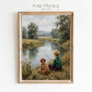 以下が含まれることがあります： 「Pure Vintage Prints」と題された額入りのヴィンテージプリントは、川辺で犬と釣りをする少年を描いています。少年は緑色のシャツとマルーン色のズボンを着ています。犬は茶色です。アートワークは木製のフレームに入っています。