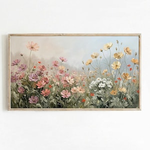 Puede incluir: Pintura floral enmarcada que representa un campo de flores coloridas. La obra de arte muestra una variedad de flores en tonos rosa, amarillo y blanco, sobre un fondo suave y borroso. La pintura está encerrada en un marco de madera de color claro.
