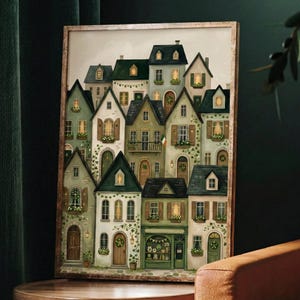 May include: A framed print depicting a charming village scene. The illustration shows a collection of houses with green, white, and brown facades, lit windows, and decorative wreaths. The artwork evokes a cosy atmosphere, with an emphasis on architectural details.
