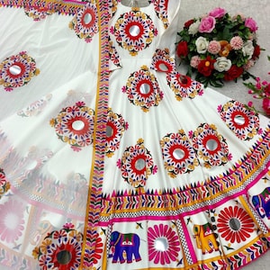 May include: White dress with colorful floral and mirror embellishments. The dress features a round neckline and short sleeves. The skirt has a border with elephant and floral designs. A matching white scarf is included.