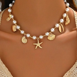 Peut inclure: Un collier de perles avec des breloques en forme de coquillages et d'étoiles de mer dorées. Le collier est composé de grosses perles blanches rondes en imitation, enfilées avec des accents métalliques dorés. Divers breloques dorées en forme de coquillages et d'étoiles de mer pendent du collier.