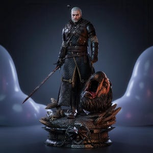 May include: A detailed collectible figurine of a white-haired warrior in black leather and chainmail armor, holding a long sword. The figure stands on a dark base featuring a wolf emblem and a severed monster head with a gaping, bloody mouth.