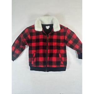 May include: A red and black plaid jacket with a white faux fur collar. The jacket has a zipper closure, two front pockets, and black cuffs and hem. The jacket is a classic style.
