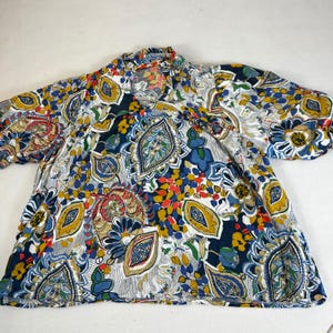 May include: A short-sleeved top with a vibrant paisley pattern in shades of blue, yellow, red, and white. The fabric has a soft, flowing appearance. The top features a round neckline and a relaxed fit, suitable for casual wear.
