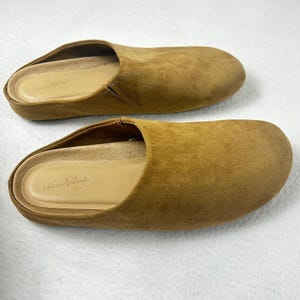 May include: Two brown suede slip-on shoes. The shoes have a rounded toe and a low heel. The interior is a light tan color. The brand name "Universal Thread" is printed on the insole.