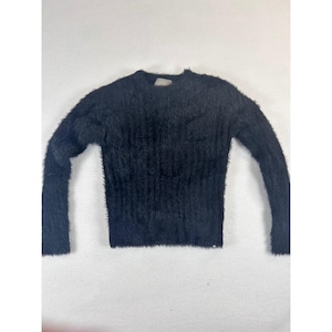May include: A black, fuzzy sweater with long sleeves. The sweater has a crew neck and a slightly fitted waist. The material appears soft and textured, with a dense, plush appearance. The garment is displayed on a white background.
