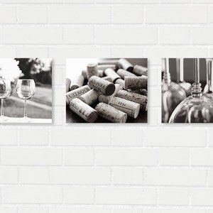 May include: A set of three black and white photographs featuring wine glasses and wine corks. The first image shows two wine glasses on a table with a blurred background of trees. The second image shows a pile of wine corks with text on them. The third image shows a close-up of wine glasses hanging upside down.