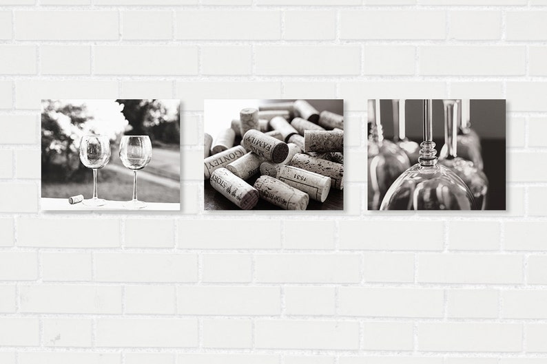 May include: A set of three black and white photographs featuring wine glasses and wine corks. The first image shows two wine glasses on a table with a blurred background of trees. The second image shows a pile of wine corks with text on them. The third image shows a close-up of wine glasses hanging upside down.