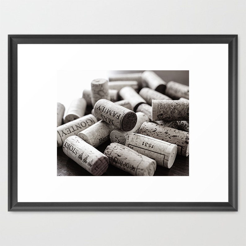 May include: A collection of wine corks in varying sizes and textures, with visible text from the wine bottles. The corks are in shades of brown and beige, creating a monochromatic image. Some corks have visible text such as "MAS FAMILY" and "STORY".