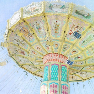 May include: A vintage-style carousel with a yellow and white painted canopy and colorful, diamond-patterned support beams. The carousel has multiple hanging seats with chains.