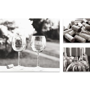 May include: Two clear glass wine glasses on a white surface with a cork on the left side of the image. The glasses are empty and have a round bowl and a long stem. The background is out of focus and shows a blurred image of trees and a grassy area.