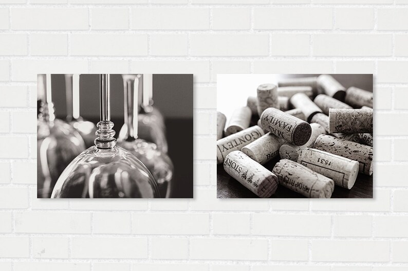 May include: Black and white photograph featuring two distinct compositions. One side showcases a close-up of wine glasses, while the other presents a collection of wine corks, some with visible text. The image is set against a white brick wall.