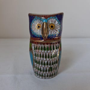 May include: A cloisonné owl figurine featuring a vibrant blue, white, and green enamel pattern with gold-toned metal wire outlines. The owl has large yellow eyes, a prominent gold-toned beak, and a segmented body design with a detachable top section.