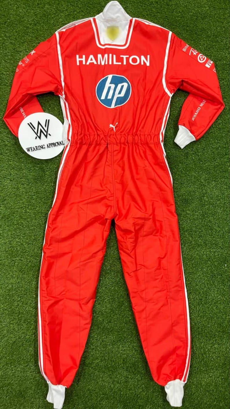 Pode incluir: Macac&atilde;o de corrida vermelho com detalhes brancos, com o nome "HAMILTON" e o logotipo da HP. O macac&atilde;o tem gola e punhos brancos, e uma faixa branca nas laterais. Ideal para desportos motorizados.