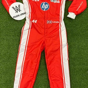 Pode incluir: Macac&atilde;o de corrida vermelho e branco com logotipos de patrocinadores, incluindo "hp", "IBM" e "UniCredit". O macac&atilde;o apresenta o n&uacute;mero "44" e o nome "Lewis". Um c&iacute;rculo branco com "WEARING APPROVAL" est&aacute; &agrave; esquerda.