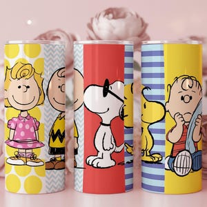 Puede incluir: Tres vasos de acero inoxidable con personajes de Peanuts. Un vaso tiene a Sally Brown, otro a Charlie Brown y el tercero a Snoopy. Cada vaso tiene un dise&ntilde;o de fondo diferente, incluyendo lunares amarillos, rayas rojas y azules.