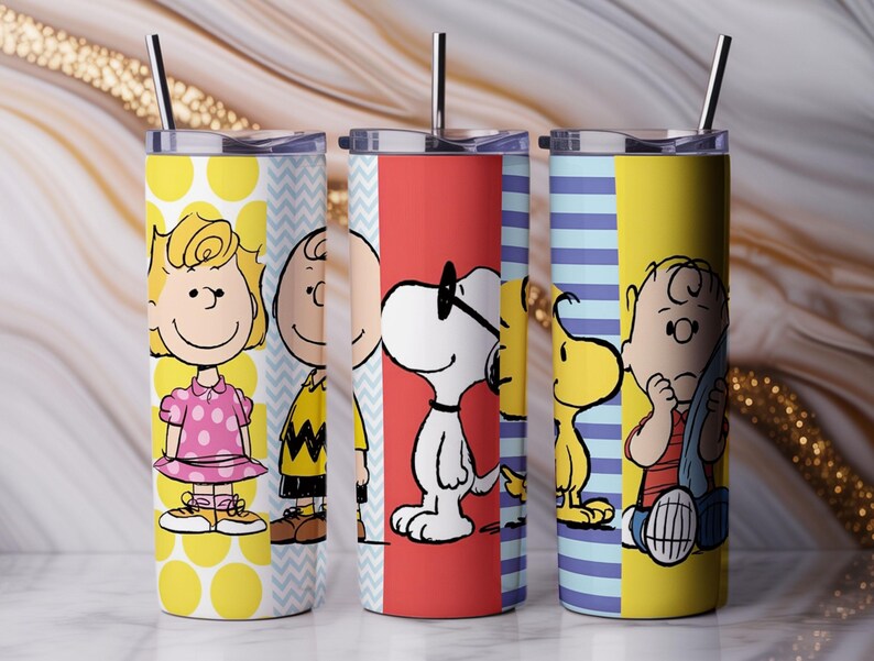 Puede incluir: Tres vasos de acero inoxidable con personajes de Peanuts. Cada vaso tiene un dise&ntilde;o diferente, incluyendo a Sally, Charlie Brown, Snoopy y Woodstock. Los vasos tienen un esquema de color amarillo, rojo y azul con una pajita negra.